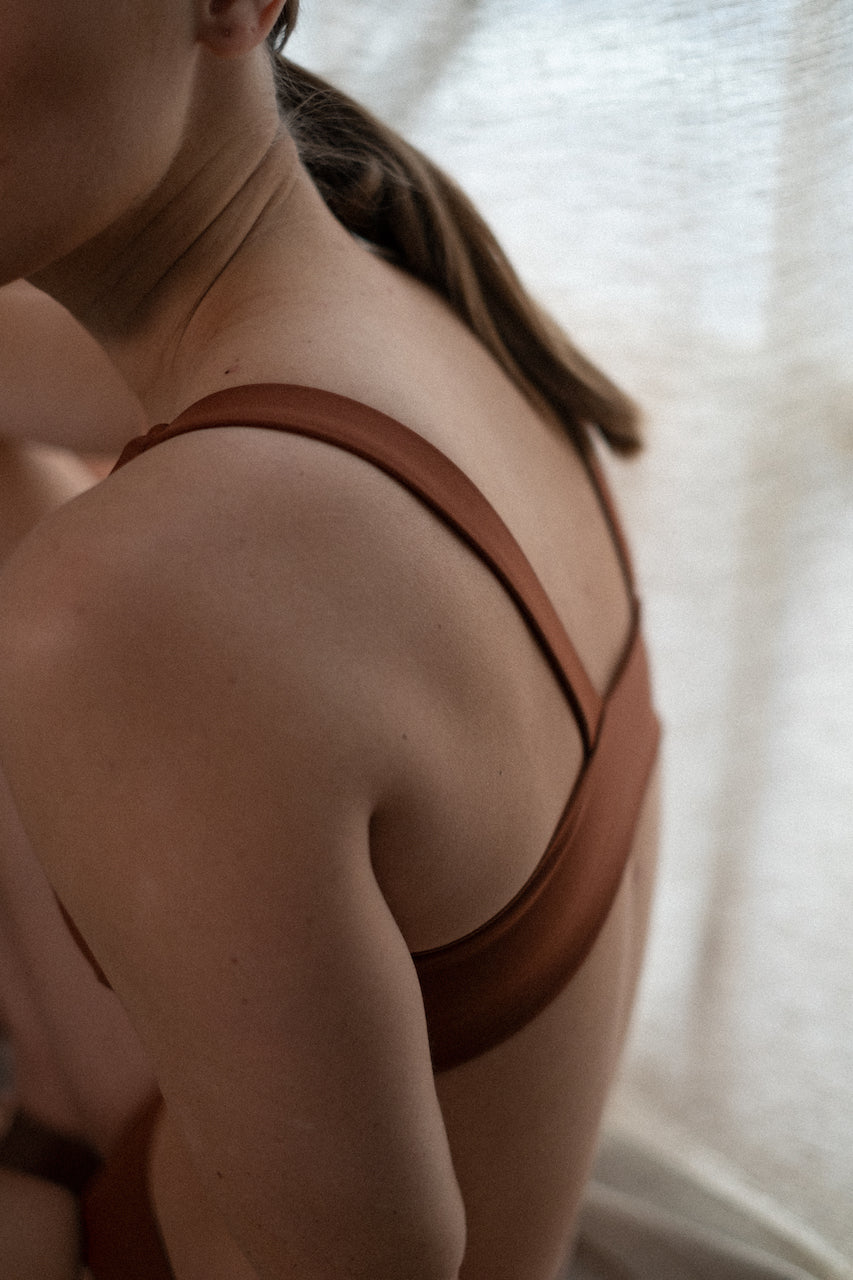 Focus in every pose—one woman in Tumla’s burnt orange swimwear align their movements with purpose during their yoga session
