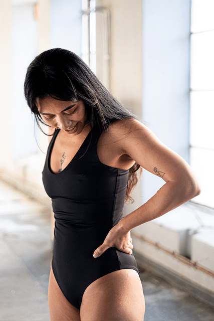 Chic black swimsuit by Tumla, worn by a brunette, designed for ultimate comfort and flexibility in the surf and beach fun
